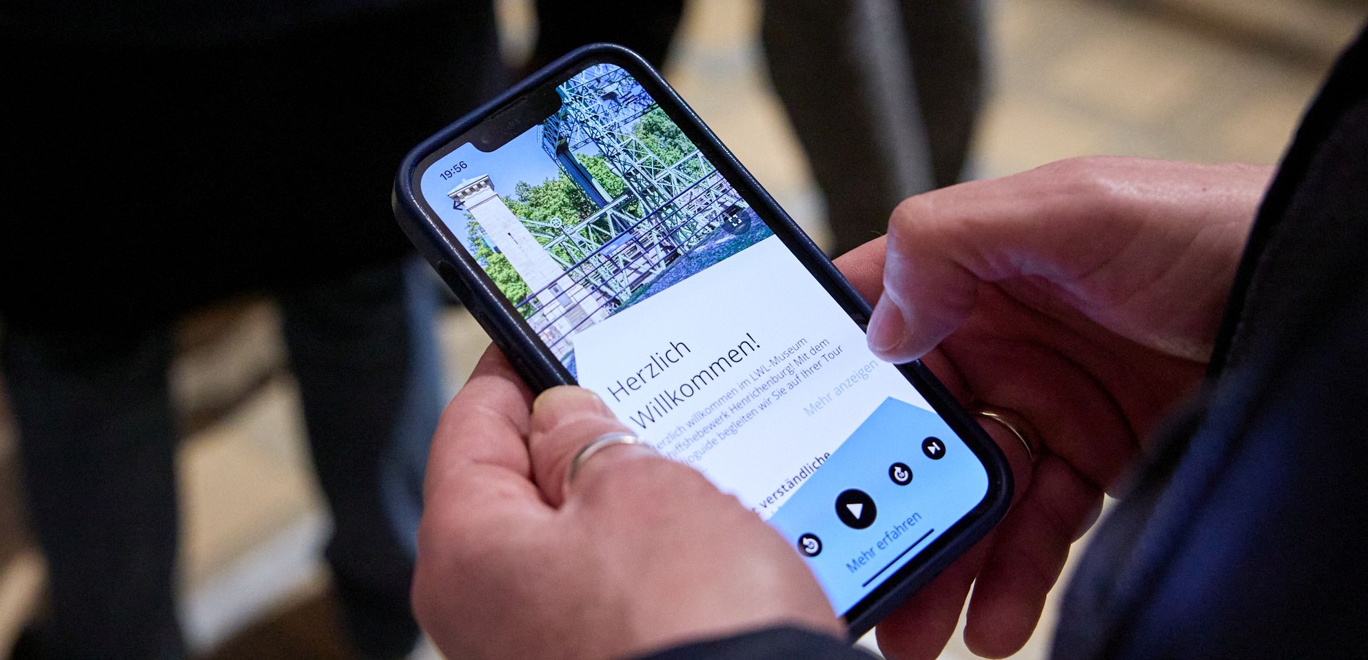 Hands holding a smartphone with the museum app.