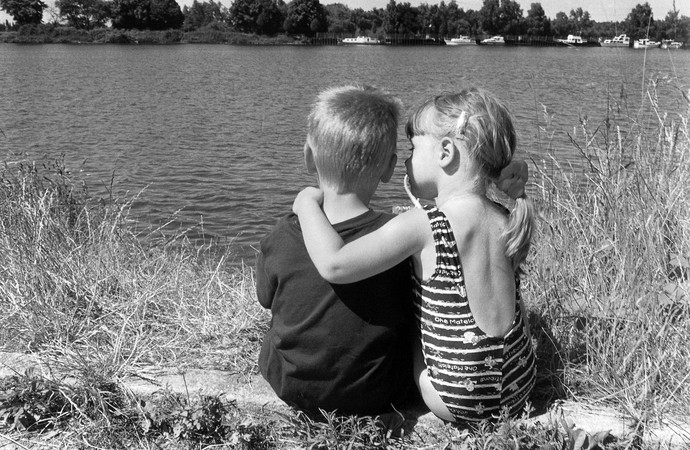 Mädchen und Junge sitzen am Kanal. Foto: Brigitte Krämer