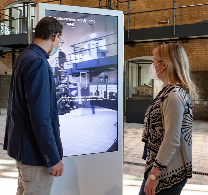 Ein Mann und eine Frau stehen an einer digitalen Tafel