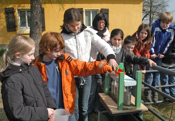 Mädchen und Jungen stehen an einer Experementierstation am Schiffshebwerk