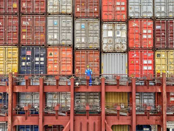 Arbeiter vor einer Wand von Containern auf einem Containerschiff.