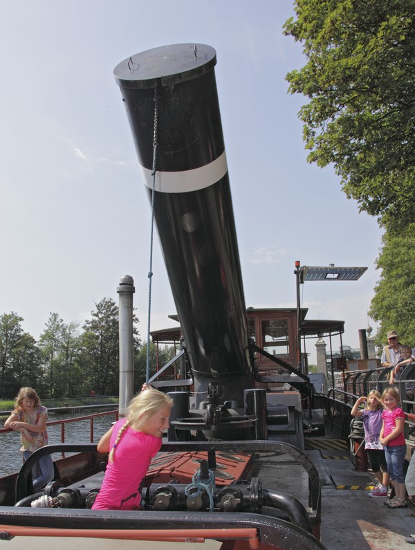 Ein Kind zieht an einem Seil, das am Schornstein eines Schiffs befestigt ist