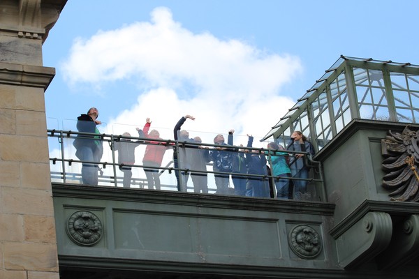 Kinder und Erwachsene stehen auf dem Hebewerk und winken in Richtung Himmel
