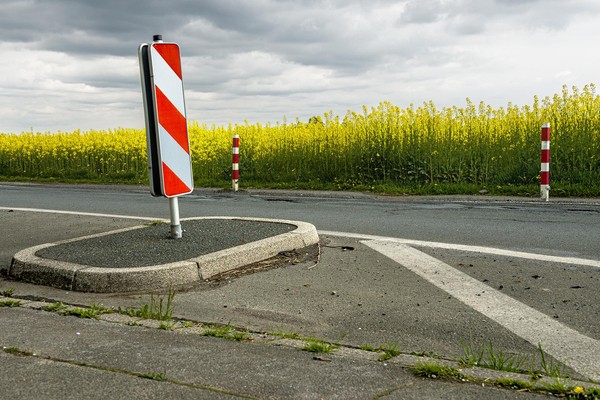 Straße mit Verkehrsinsel, auf der eine rot-weiße Barke steht