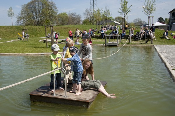 Kinder auf einem Flos auf dem Wasserspielplatz.