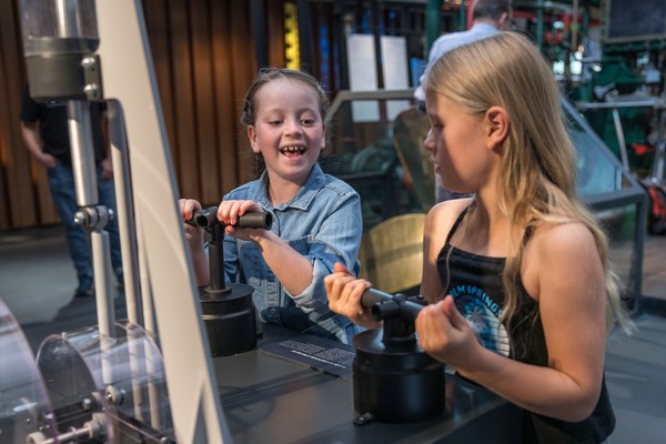 2 Mädchen  stehen an einer Experementierstation in der Dauerausstellung
