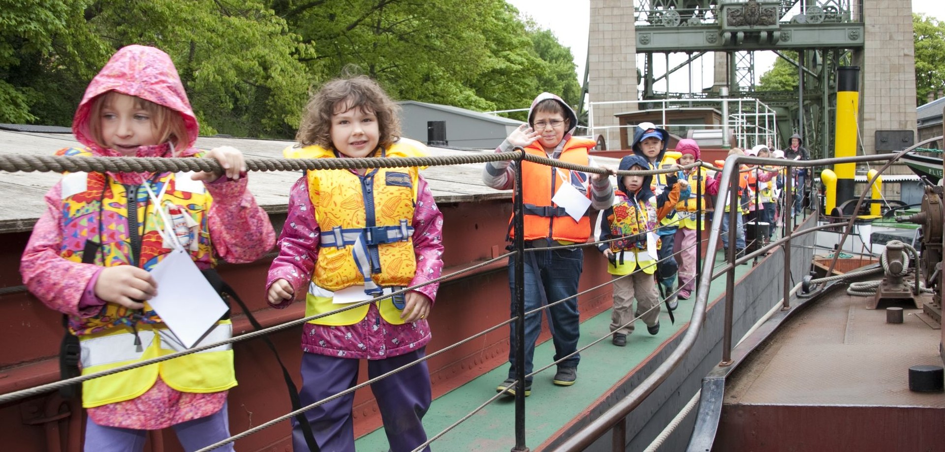 Kinder mit Rettungsweste gehen an Deck des Museumsschiffes.