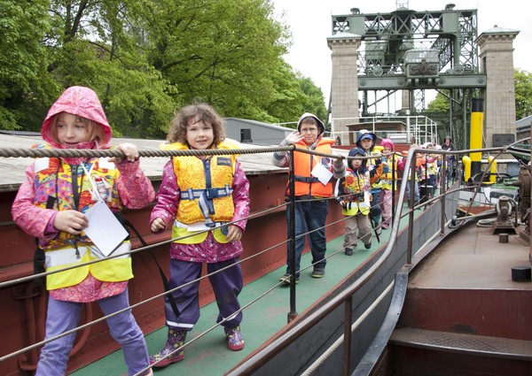 Kinder mit Schwimmwesten laufen auf dem Museumsschiff.