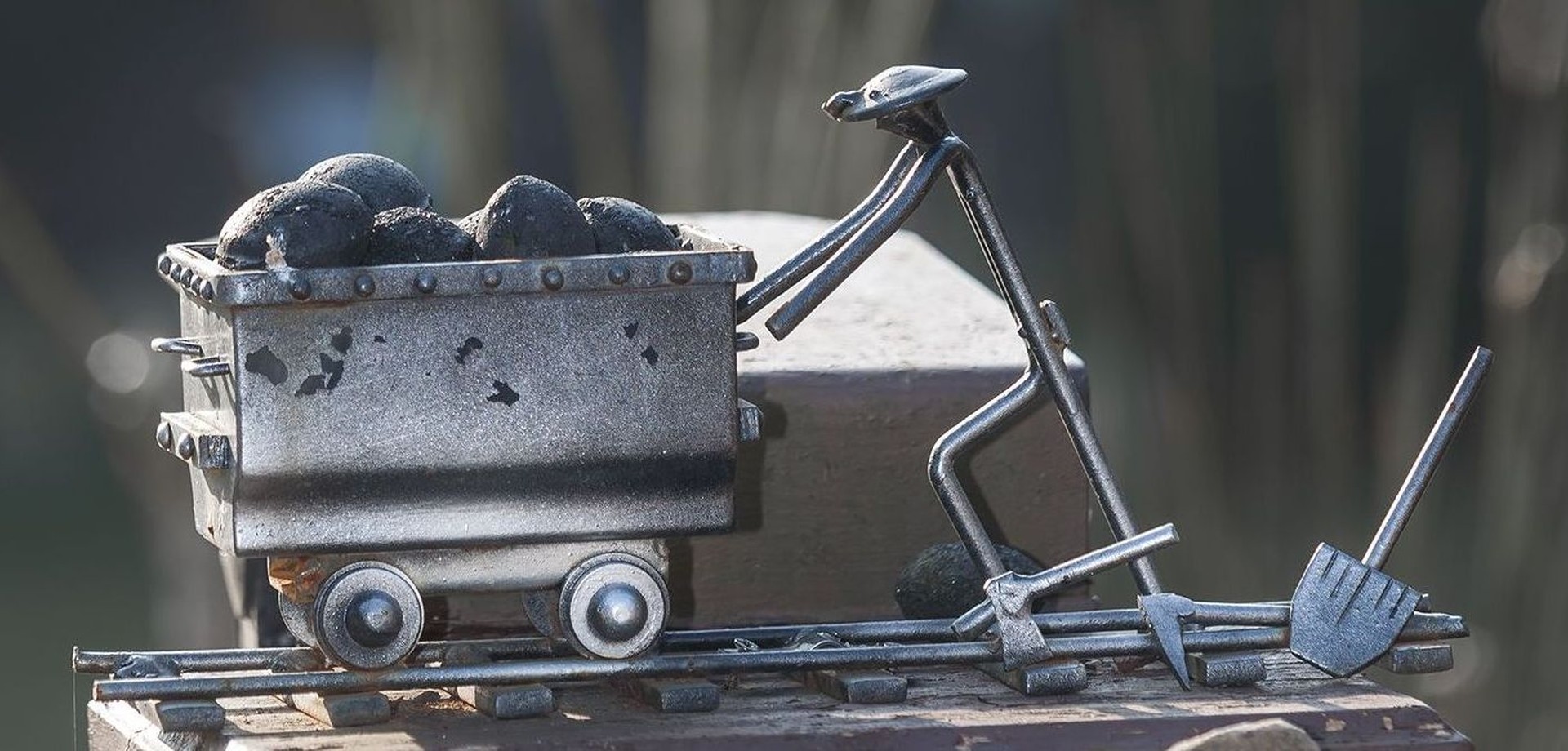 Eisen-Skulptur: Ein Männchen schiebt einen Grubenwagen